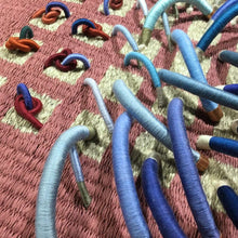 Load image into Gallery viewer, woven textile relief sculpture detail 3, vibrant playful blue and red colors on a dusty rose background