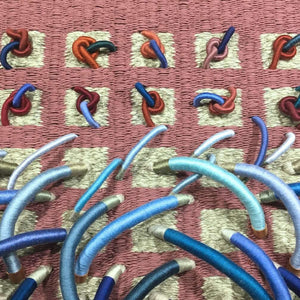 woven textile relief sculpture detail 1, vibrant playful blue and red colors on a dusty rose background